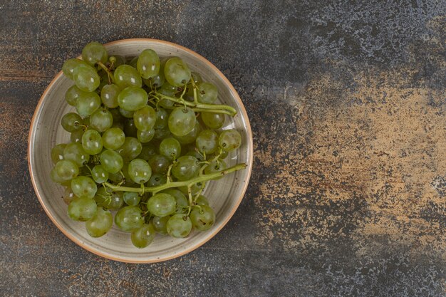 Verse groene druiven op keramische plaat.