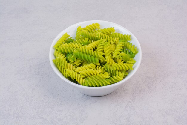 Verse groene ongekookte spiraalvormige macaroni op witte plaat