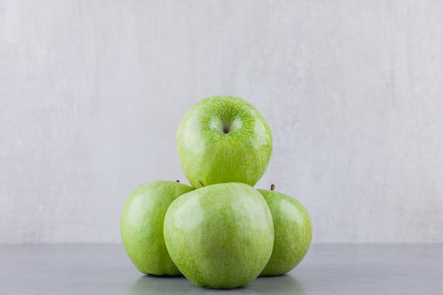 Verse groene rijpe appelvruchten die op een steenlijst worden geplaatst.