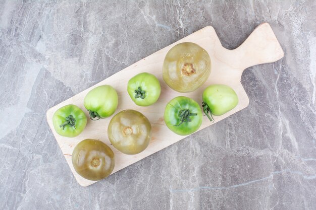 Gratis foto verse groene tomaten en ingelegde tomaten op een houten bord.