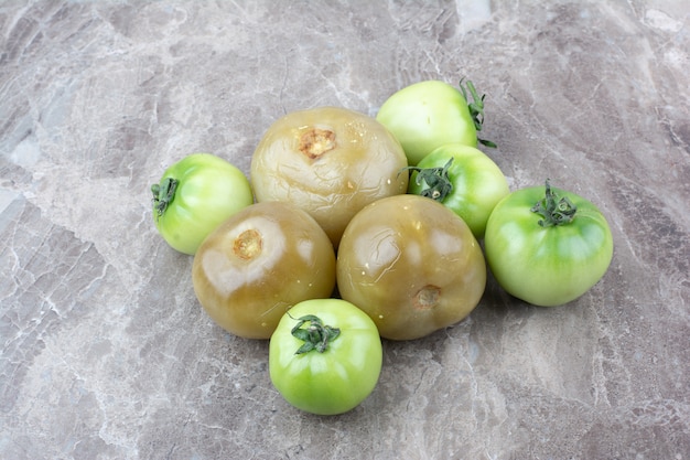 Verse groene tomaten en ingelegde tomaten op marmeren oppervlak.