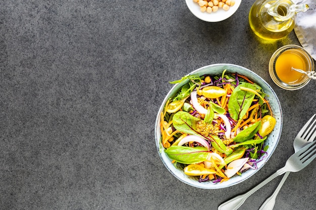 Verse groente- en fruitsalade in een plaat op zwarte steen. Bovenaanzicht