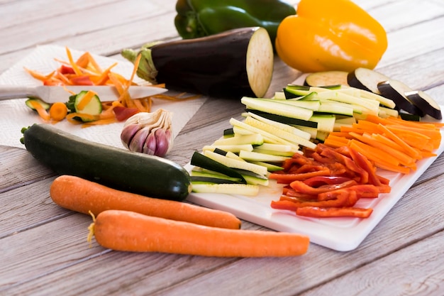 Verse groenten op een houten tafel met een mix van gesneden wortel, courgette, aubergine en paprika