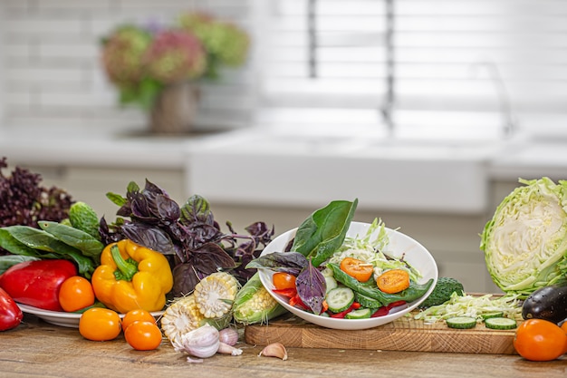 Verse groenten tijdens het bereiden van salade op een houten tafel.