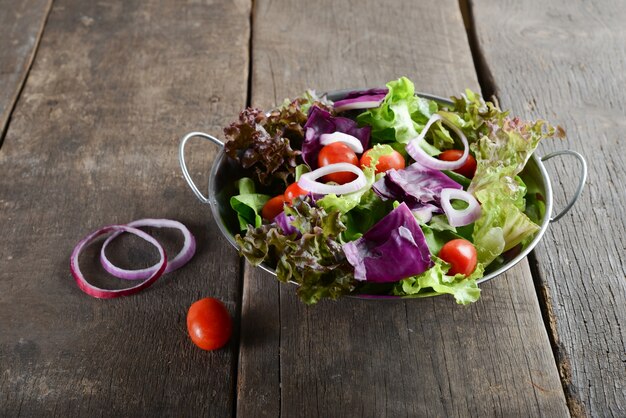 Gratis foto verse groentesalade in de kom met rustieke oude houten achtergrond.