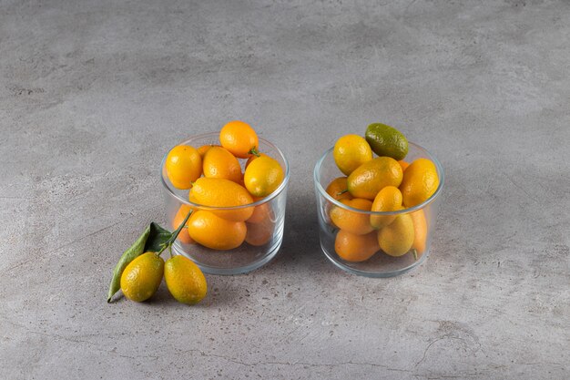 Verse hele citrusvruchten cumquatvruchten met bladeren die in kom worden geplaatst