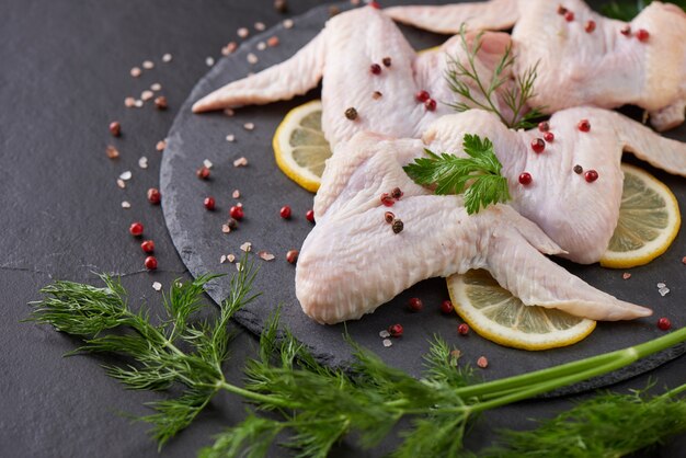 verse kippenvleesporties voor koken en barbecueën met verse kruiden. Ruw ongekookt kippenbeen op scherpe raad.