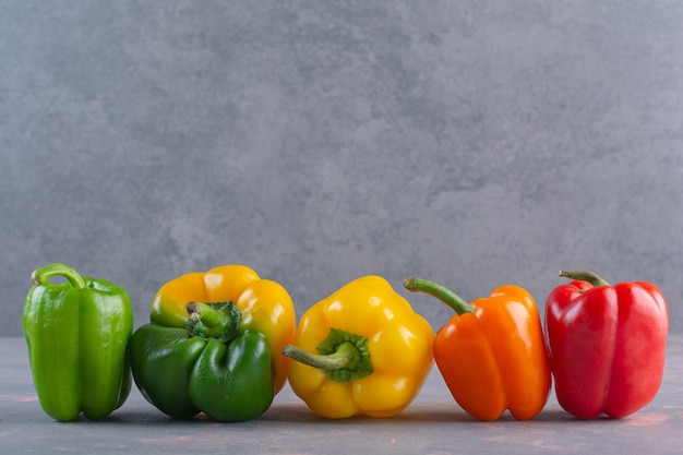 Verse kleurrijke biologische paprika's die op stenen oppervlak worden geplaatst