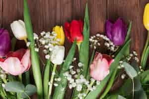 Gratis foto verse kleurrijke tulpen en de adembloem van de baby op houten bureau