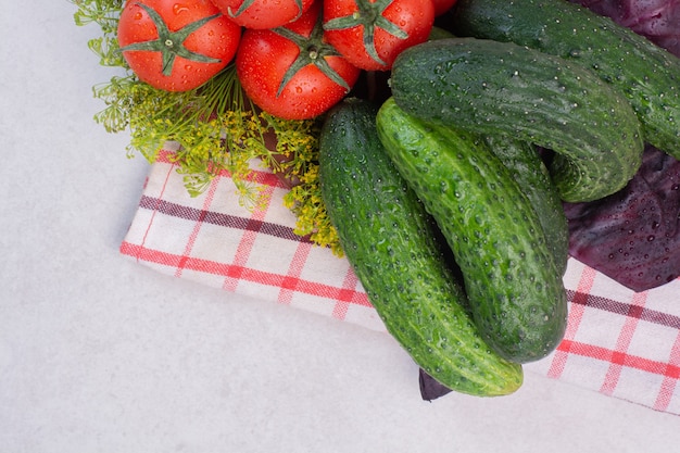 Verse komkommers, tomaten en basilicum op tafellaken