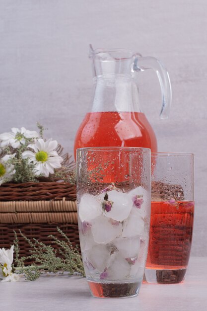 Verse limonade in glas en ijsblokjes op witte tafel.