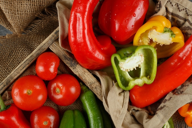 Verse pepers en tomaten in een rustieke lade.