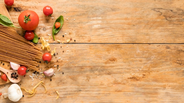Gratis foto verse rauwe italiaanse ingrediënten met spaghetti pasta over geweven tafel
