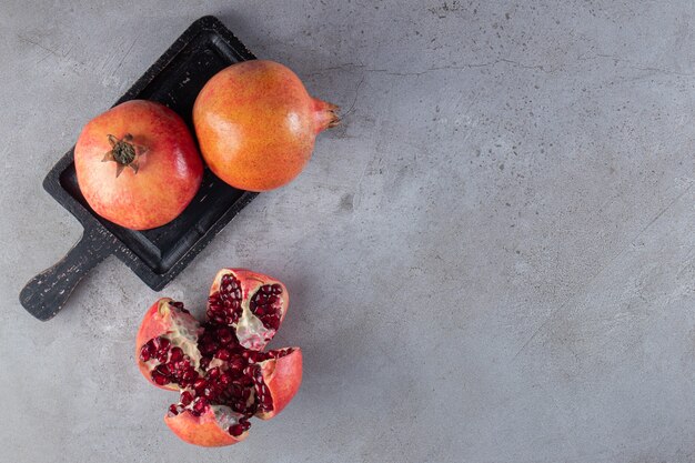 Verse rijpe granaatappels met zaden op een zwarte bord.