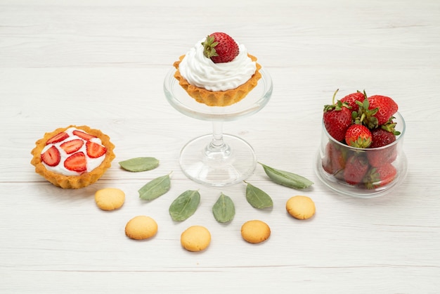 verse rode aardbeien zachte en heerlijke bessen met cakes en koekjes op licht bureau fruit bessen rode kleur versheid