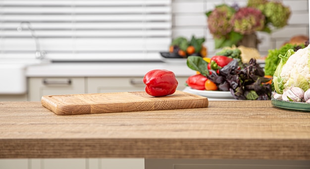 Verse rode paprika op een houten plank tegen de achtergrond van een keukenbinnenland.