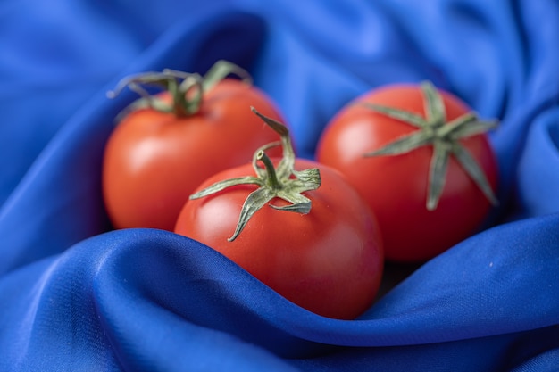 Gratis foto verse rode tomaten op blauw tafellaken.