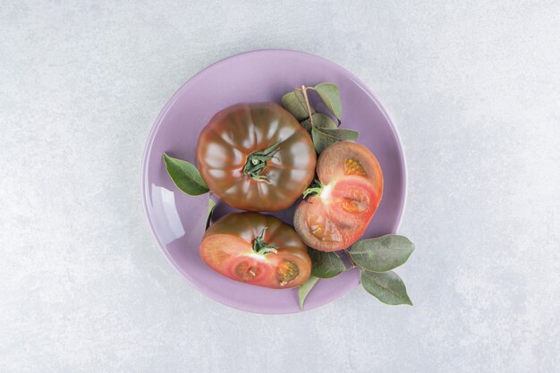 Verse tomaat in de plaat op het marmeren oppervlak