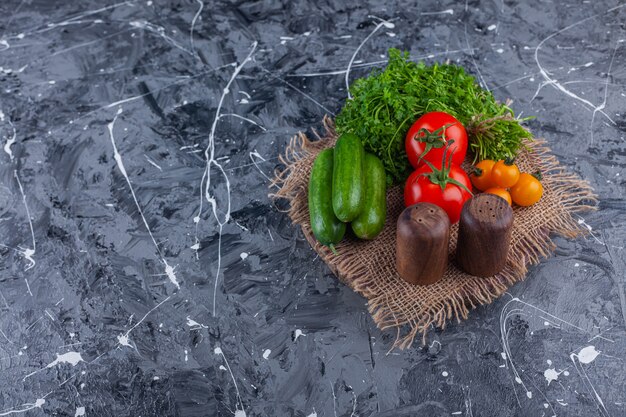 Verse tomaten, komkommers en peterselieblaadjes op marmeren oppervlak.