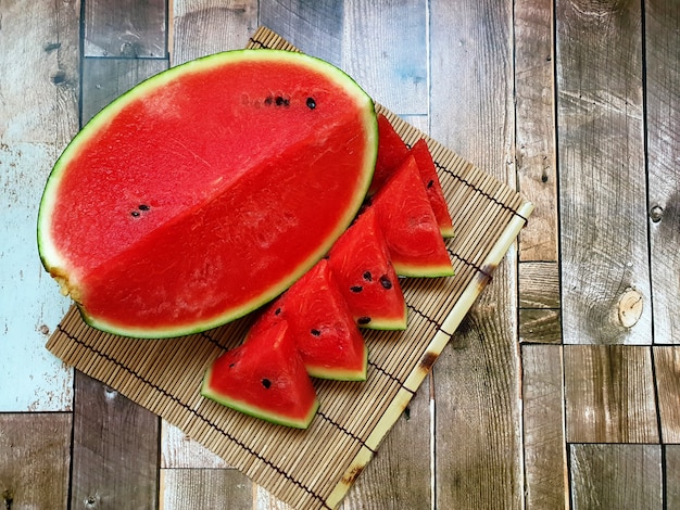 Verse watermeloenplak op een bamboemat en een houten achtergrond