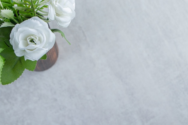 Verse witte bloemen in een houten kruik, op de witte tafel.