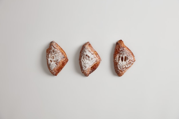 Verse zelfgemaakte kleine bladerdeegbroodjes gevuld met iets lekkers, gepoederd met suiker, geïsoleerd op een witte achtergrond. Heerlijke zoete gebakjes. Vers smakelijk bakken. Junkfood en voeding concept