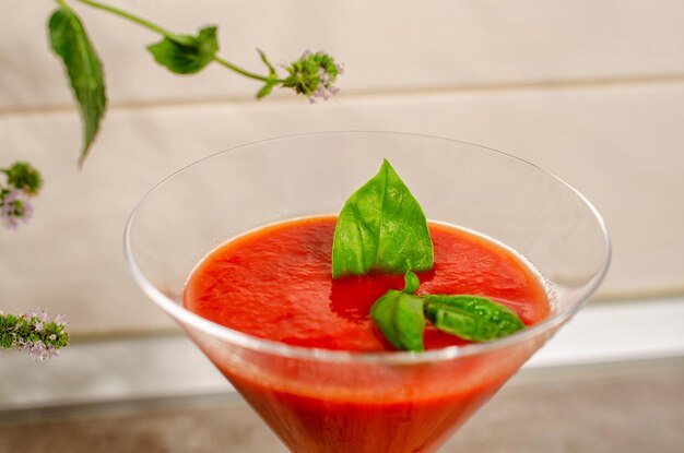 Verse zelfgemaakte rauwe biologische rode tomatensap met groene basilicum lea