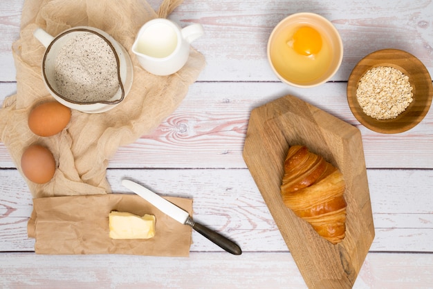 Versgebakken croissant met ingrediënten op houten bureau