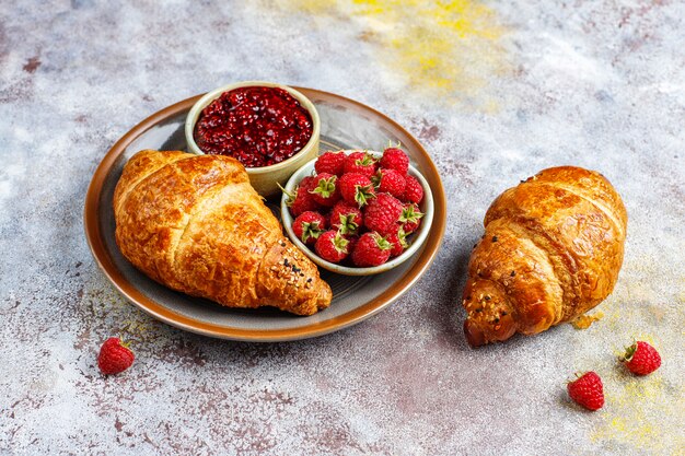 Versgebakken croissants met frambozenjam en frambozenfruit.