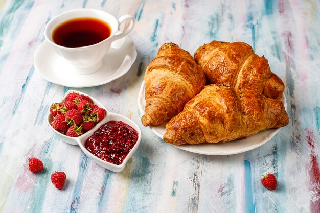 Versgebakken croissants met frambozenjam en frambozenfruit.