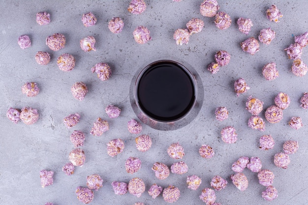 Verspreide massa gekonfijte popcorn rond een koud glas cola op marmeren achtergrond. hoge kwaliteit foto