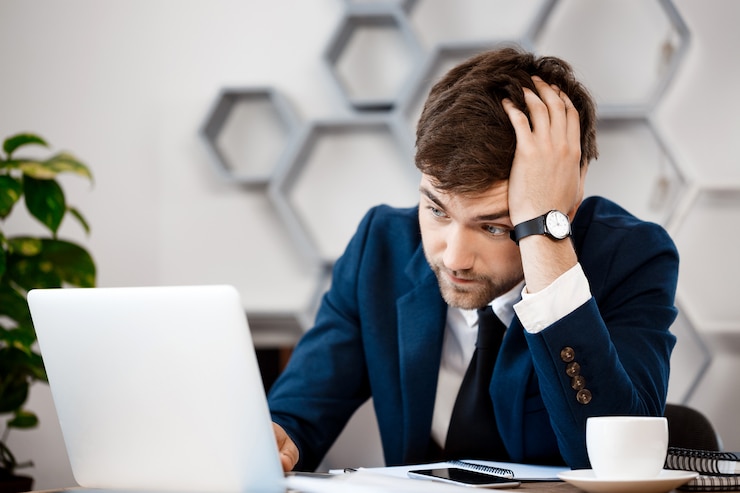 Gratis Foto verstoor jonge zakenmanzitting bij laptop, bureauachtergrond.