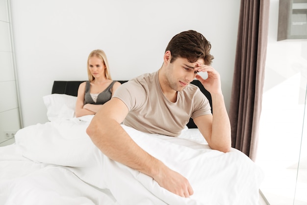 Verstoorde manzitting met zijn droevige vrouw in bed thuis