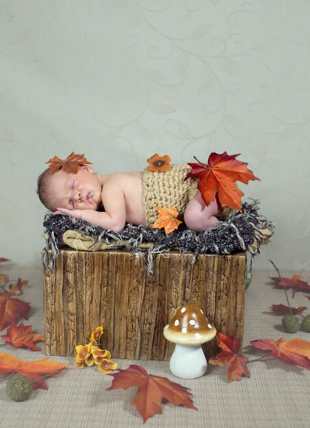 Vertica shot van een slapende baby die een gebreide luier draagt met herfstbladeren