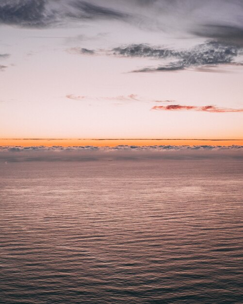 Verticaal beeld van een prachtig uitzicht op de oceaan met golven en een oranje horizon