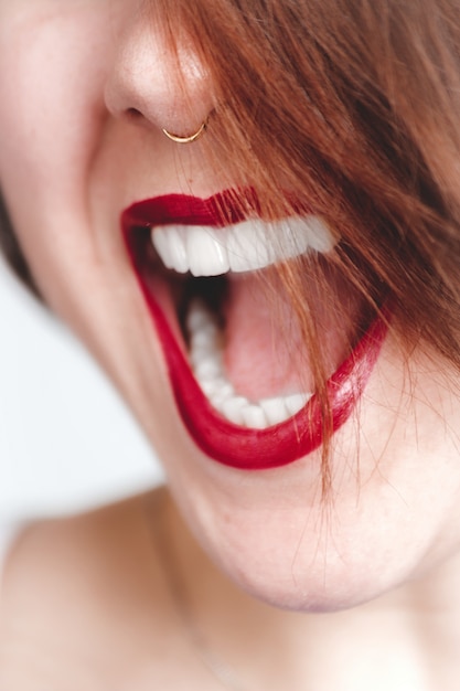 Verticaal close-upschot van een wijfje met rode lippenstift die haar mond opent