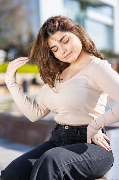 Verticaal portret van een jong meisje Jong meisje dat in het park zit en haar hand op haar middel legt Hoge kwaliteit foto