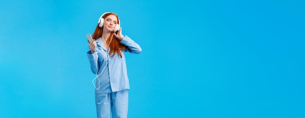 Verticaal portret van volledige lengte charmant en teder vrouwelijk schattig roodharige vrouw in nachtkleding nauwlettend in de gaten