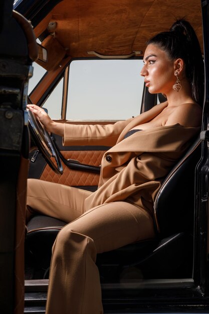Verticaal portret van zelfverzekerd jong model zittend op een bestuurdersstoel in de auto Foto van hoge kwaliteit
