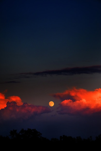 Verticaal schot van de maan en vuurwolken in de donkere hemel