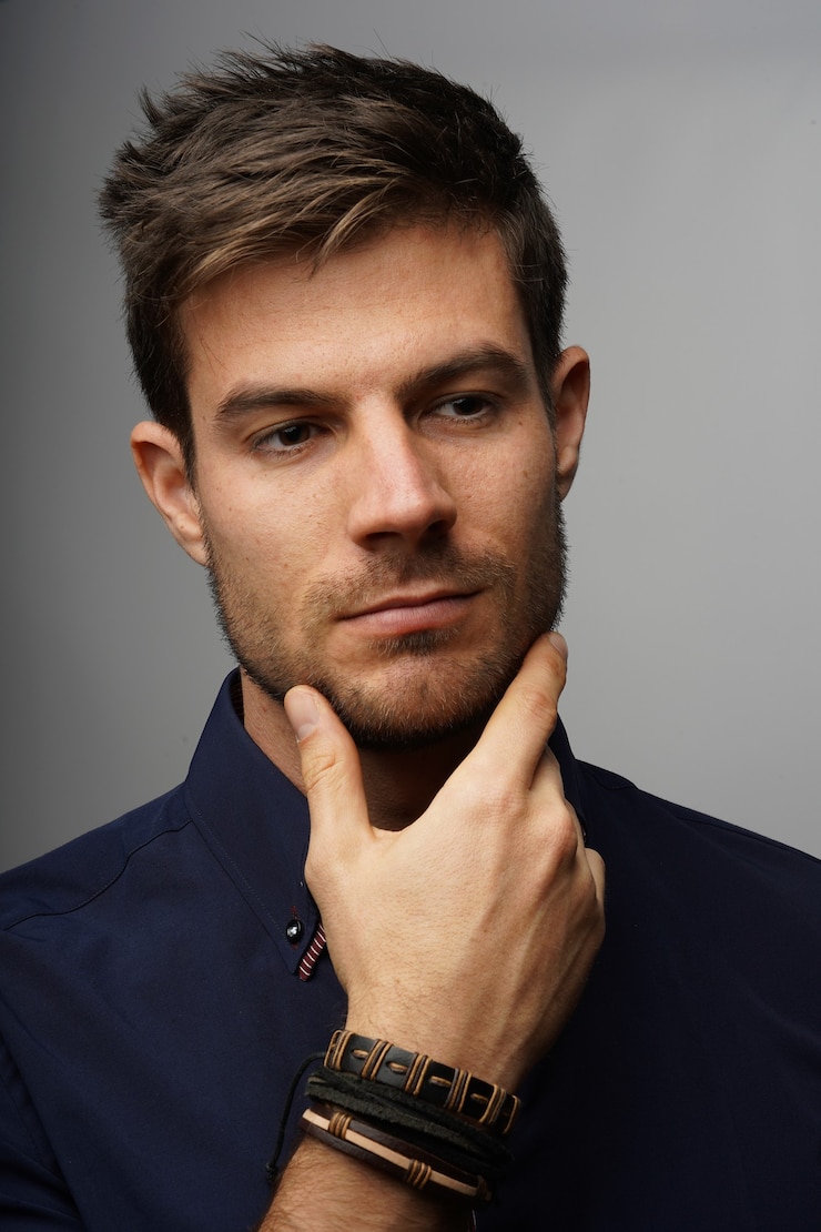 Gratis Foto verticaal schot van een jonge zakenman die zachtjes zijn kin vasthoudt terwijl hij denkt
