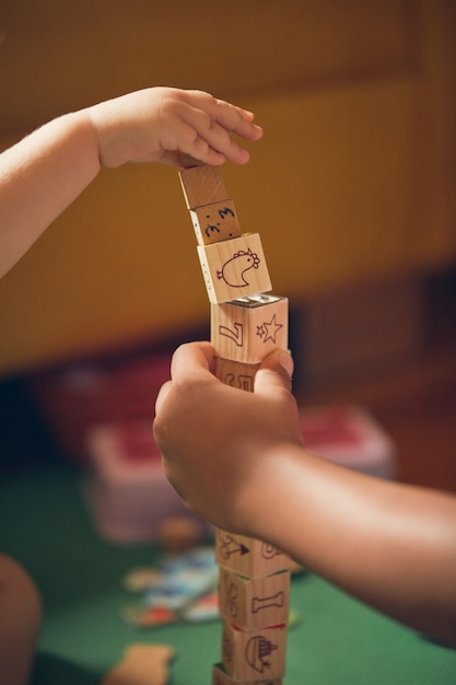 Gratis foto verticaal schot van een kind en een volwassene die met educatieve houten kubussen op de vloer spelen