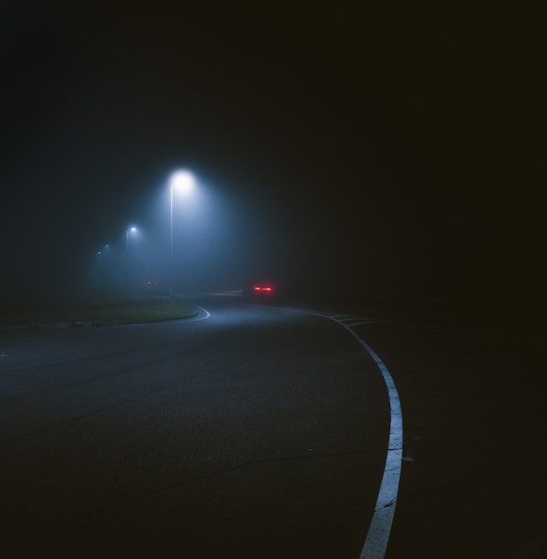 Verticaal schot van een lantaarnpaal bij de straat, vastgelegd tijdens de nacht