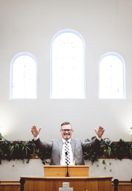 Gratis foto verticaal schot van een man in een pak die woorden van de heilige bijbel predikt bij het altaar van een kerk