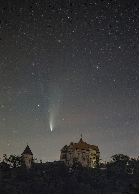 Verticaal schot van een Neowise-komeet die over het Pernstejn-Kasteel in de Tsjechische Republiek vliegt