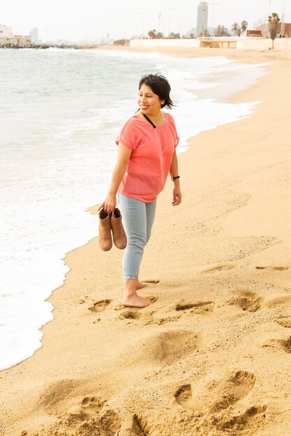 Verticaal schot van een Spaanse vrouw die op zand loopt op het strand van Barceloneta, Barcelona, Spanje