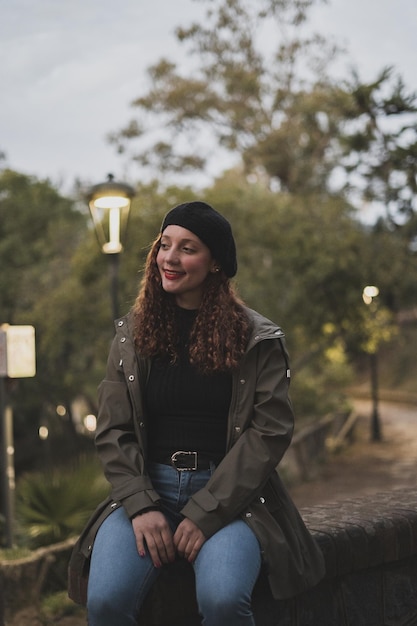 Verticaal schot van een vrouw met een kaki jasje en een zwarte warme muts in het park