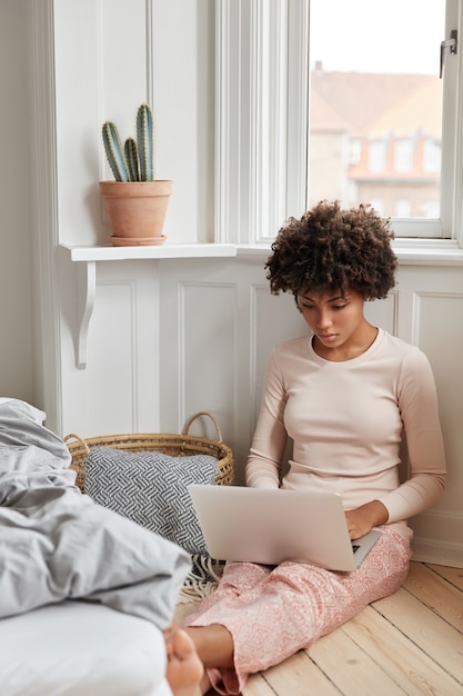 Gratis foto verticaal schot van het geconcentreerde jonge vrouw stellen thuis