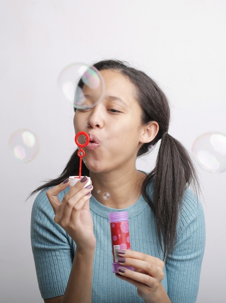 Verticaal schot van jonge vrouwelijke blazende zeepbellen