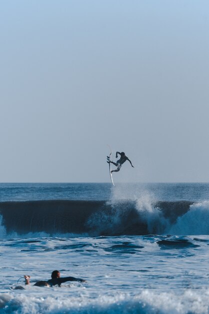 Verticaal schot van surfers die trucs doen in de oceaan die de golven overnemen